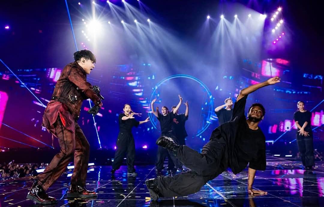 林俊傑站在台北大巨蛋舞台上，背景投影與燈光交錯呈現沉浸式視覺效果