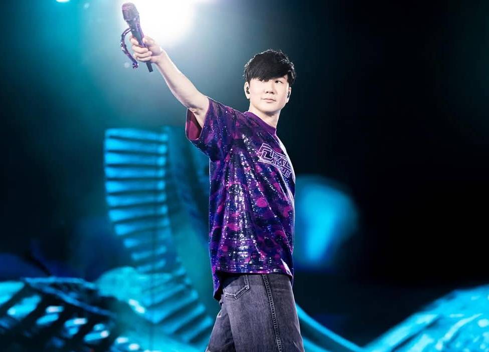 林俊傑站在台北大巨蛋舞台上，背景投影與燈光交錯呈現沉浸式視覺效果