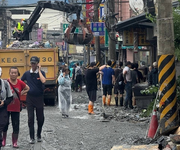 志工於災區現場佩戴口罩進行清理工作，塵土飛揚中努力守護家園