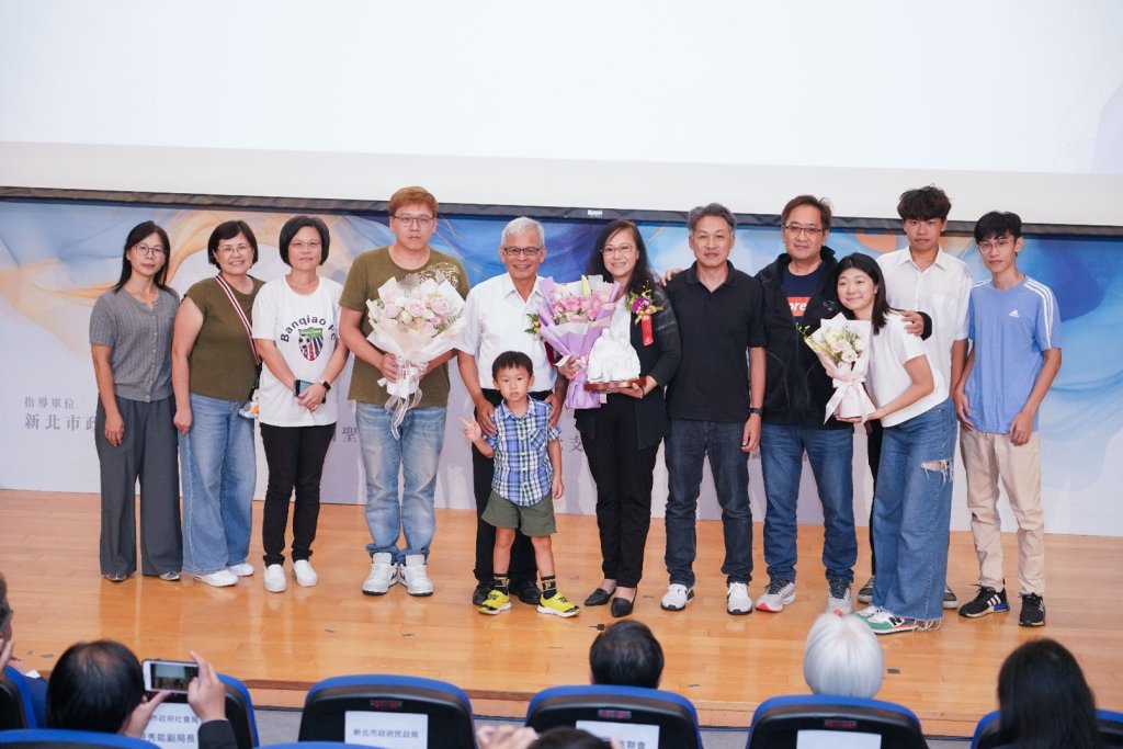 照片顯示四位溫暖人間獎得主在典禮上合影，背景為溫馨布置舞台與耶穌基督後期聖徒教會標誌