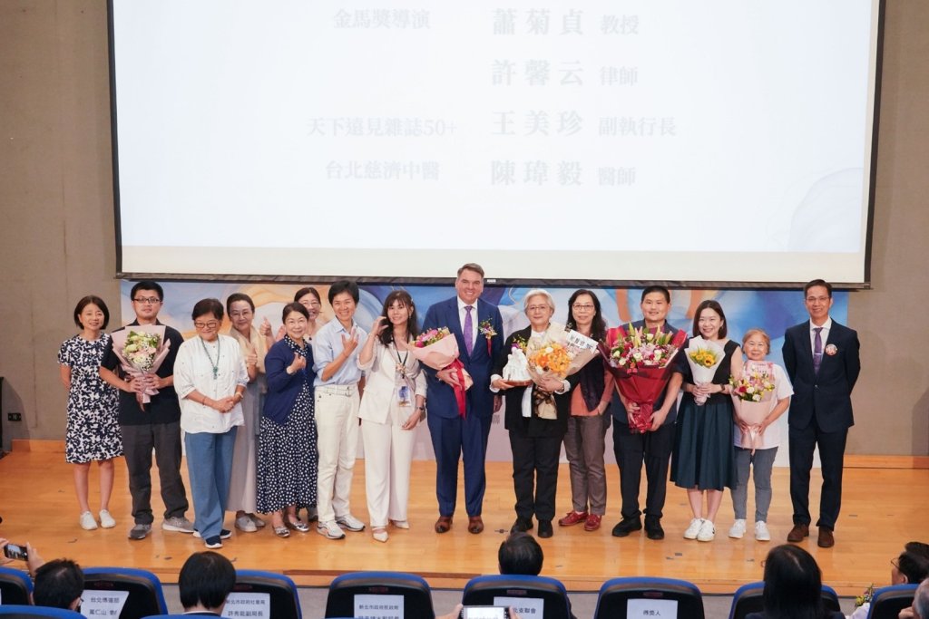 照片顯示四位溫暖人間獎得主在典禮上合影，背景為溫馨布置舞台與耶穌基督後期聖徒教會標誌