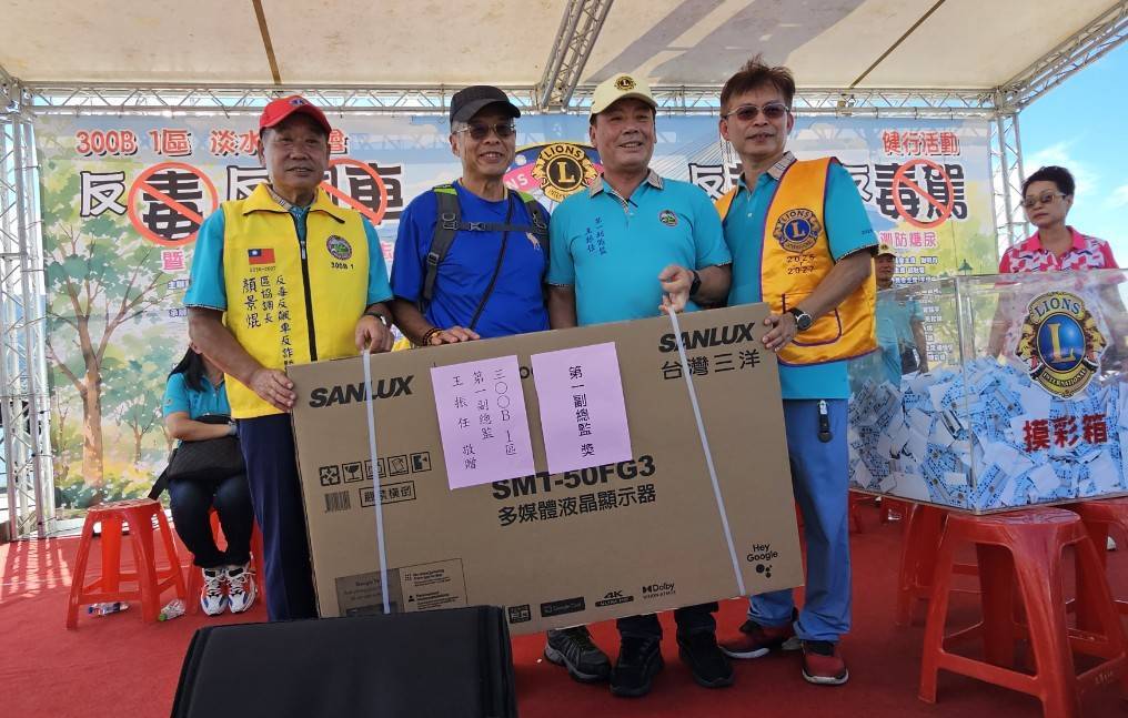 淡水獅子會公益健走現場，民眾在漁人碼頭舞台前舉手參與互動