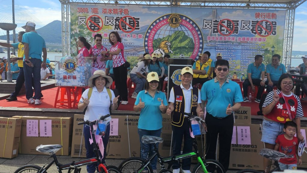 淡水獅子會公益健走現場，民眾在漁人碼頭舞台前舉手參與互動