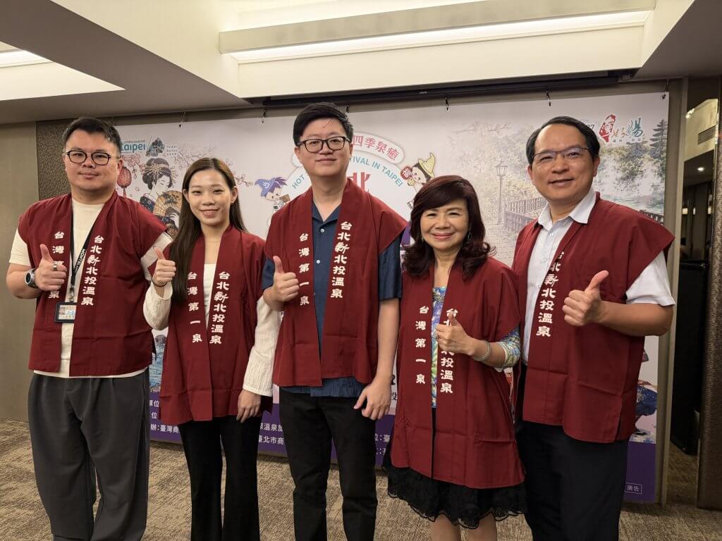 2026臺北溫泉季記者會合照，與會者及身穿彩色服裝的表演者手持鳴子